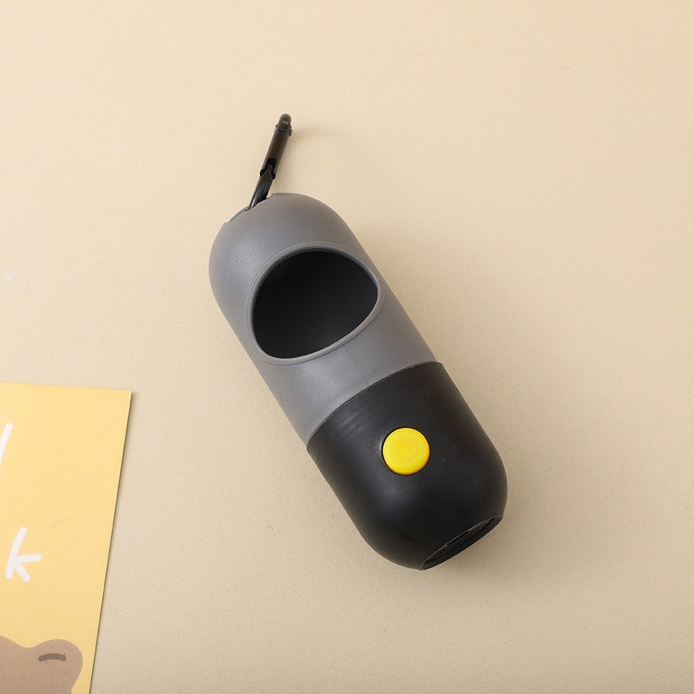 Gray and black pet waste bag dispenser with a yellow button on a beige background