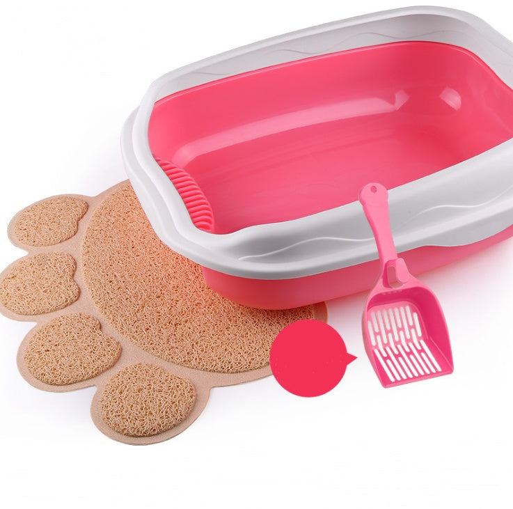 Pink pet litter box with scoop and mat on a white background