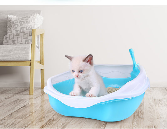 Kitten inside a blue pet litter box on a wooden floor with a chair in the background.