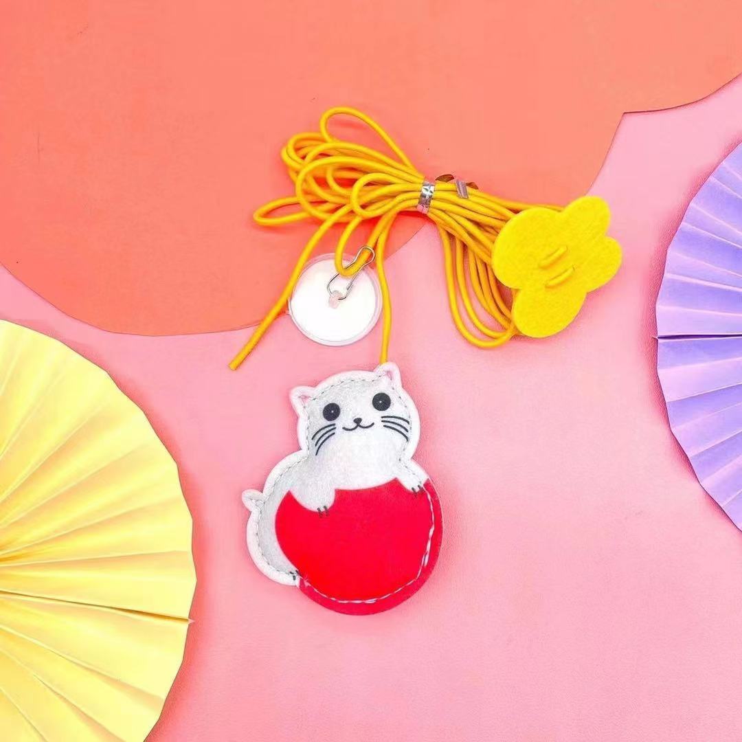 Cat-shaped phone charm with yellow lanyard on a pink background