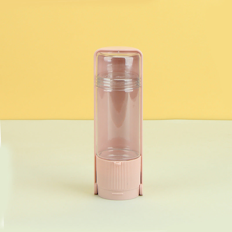 Pink water bottle with clear lid on a yellow and beige background