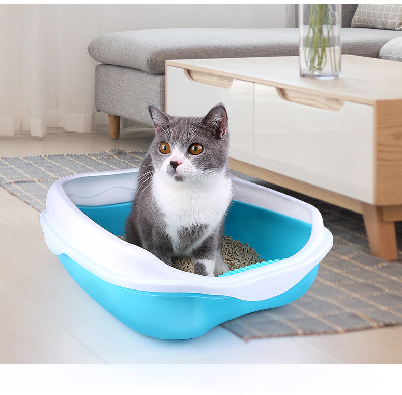 Cat sitting inside a blue and white litter box in a living room.