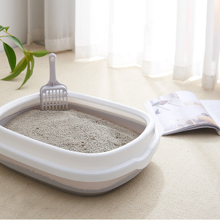Cat litter box with scoop on a light-colored floor