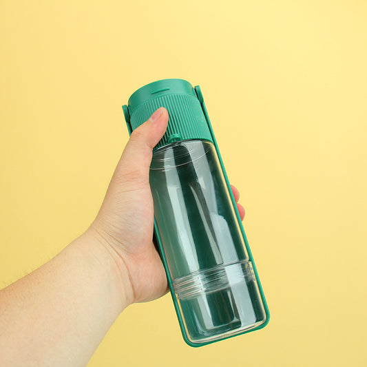 Hand holding a green water bottle with a clear lid against a yellow background