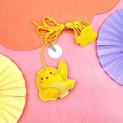 Yellow duck-shaped pouch with a lanyard on a pink and orange gradient background