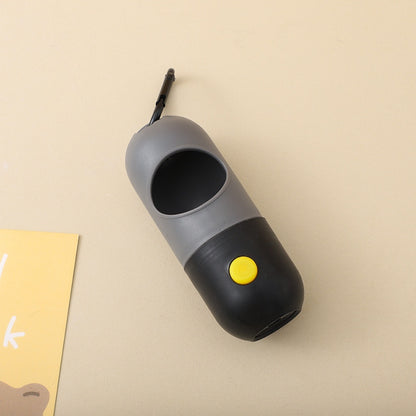 Gray and black pet waste bag dispenser with a yellow button on a beige background