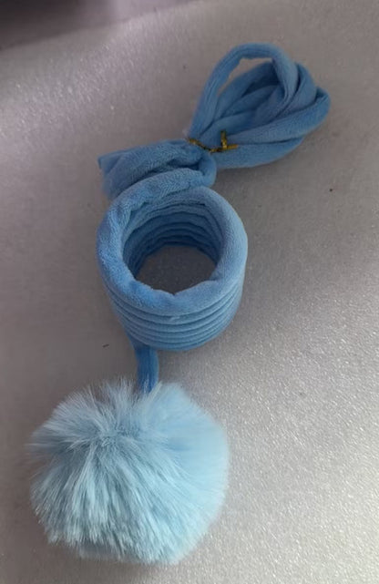 Blue hair ties with a pom-pom on a light gray surface