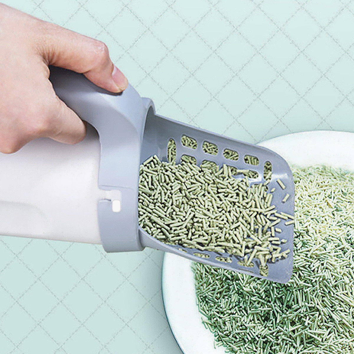 Hand using a tool to sort green cat food into a bowl on a light blue quilted background