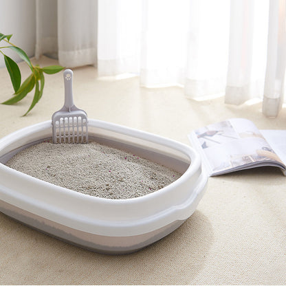 Cat litter box with scoop on a light-colored floor